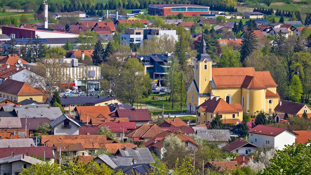 A town with red-roofed houses, a church, and a mix of modern and traditional buildings.