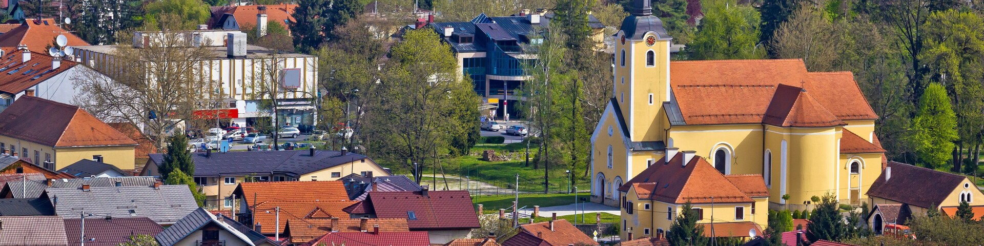 A town with red-roofed houses, a church, and a mix of modern and traditional buildings.