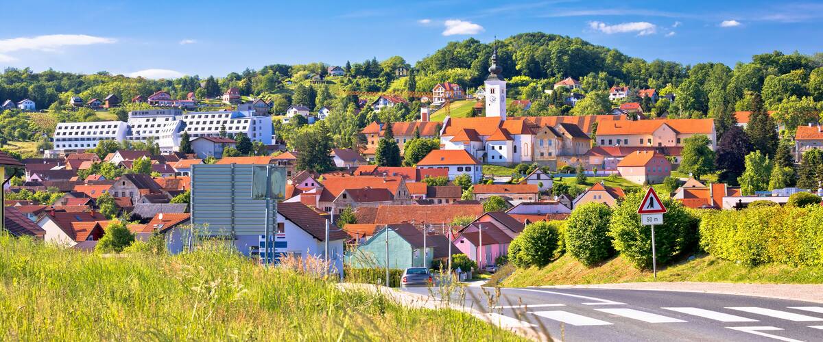 A town with red-roofed houses, a church, and a hill with greenery.