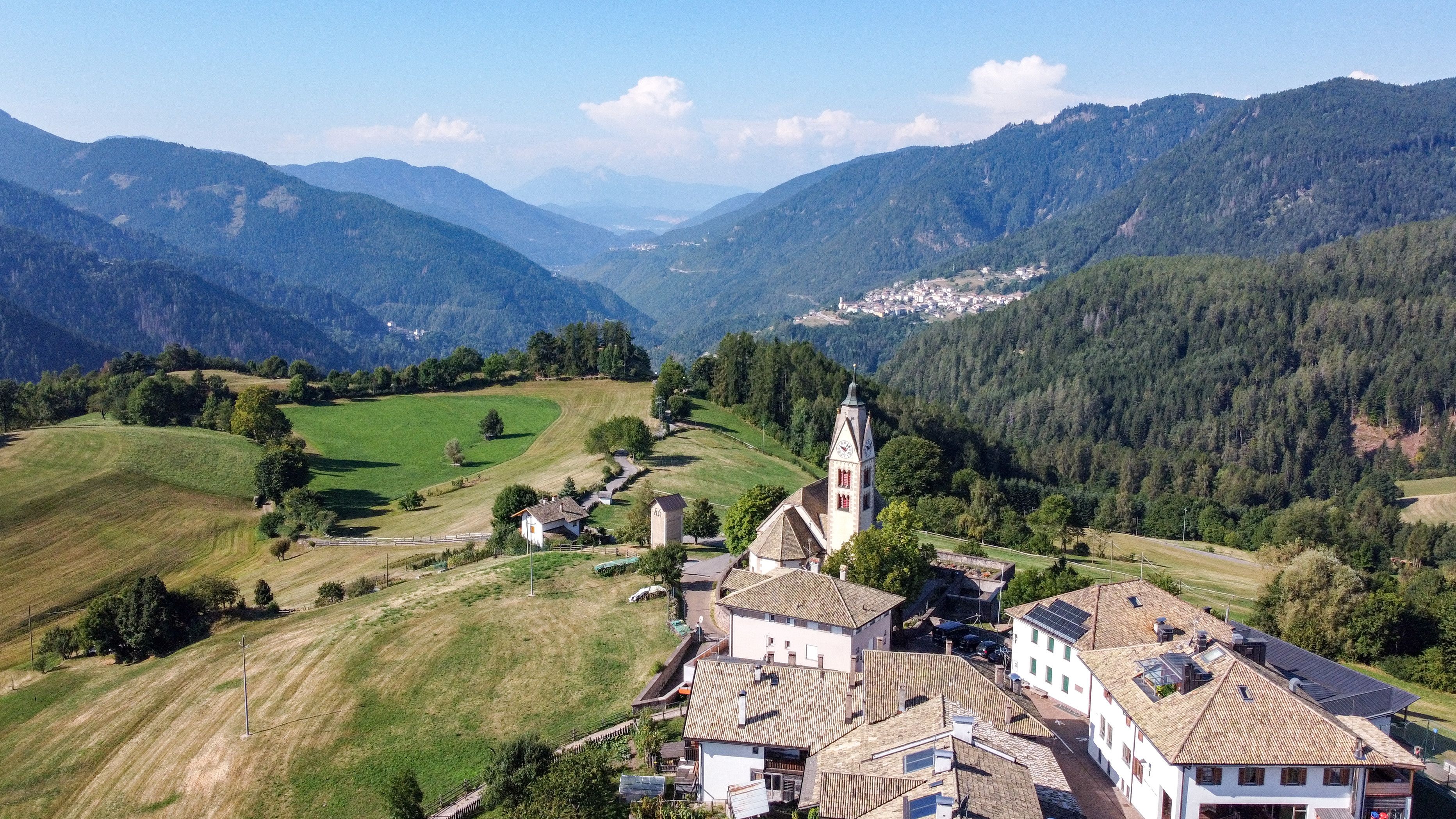 A mountainous landscape with a church, houses, and a valley.
