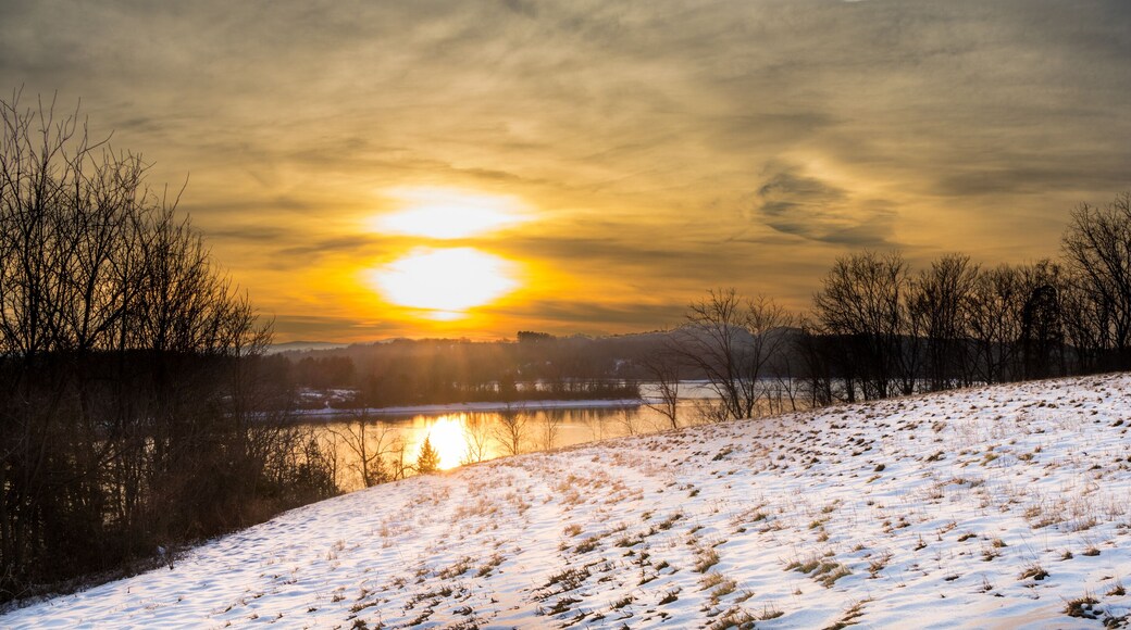 Panoramic view of a sunrise over Blue Marsh Lake with a snowy field in the foreground