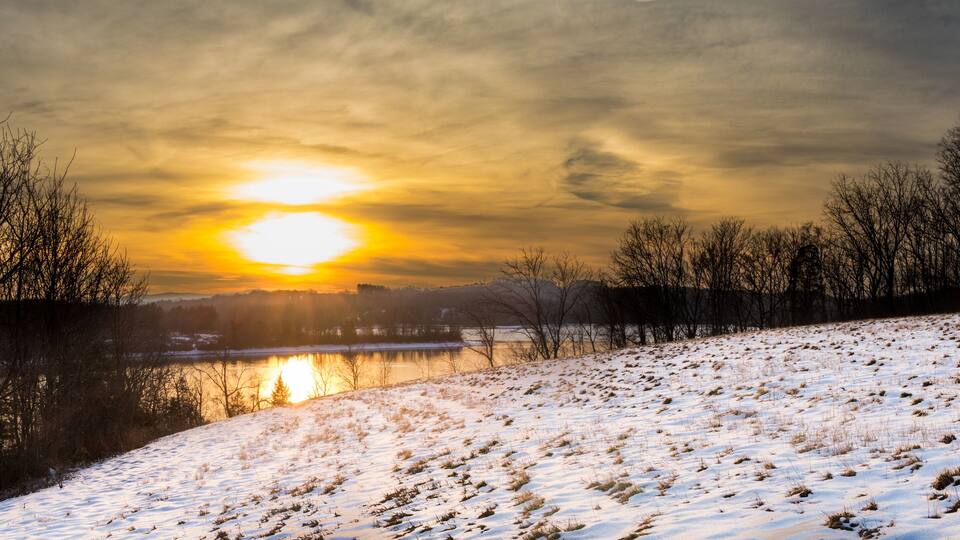 Panoramic view of a sunrise over Blue Marsh Lake with a snowy field in the foreground