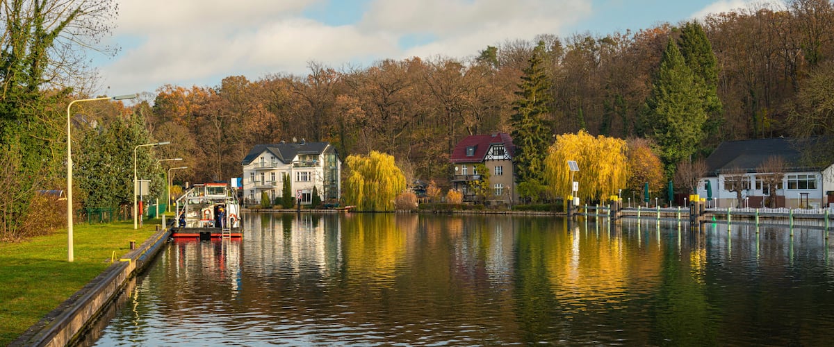 A calm lake with houses and trees reflecting on the water.