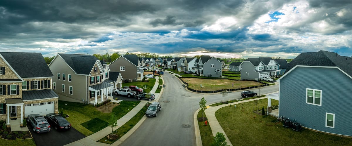 A suburban neighborhood with houses, a road, and a cloudy sky.