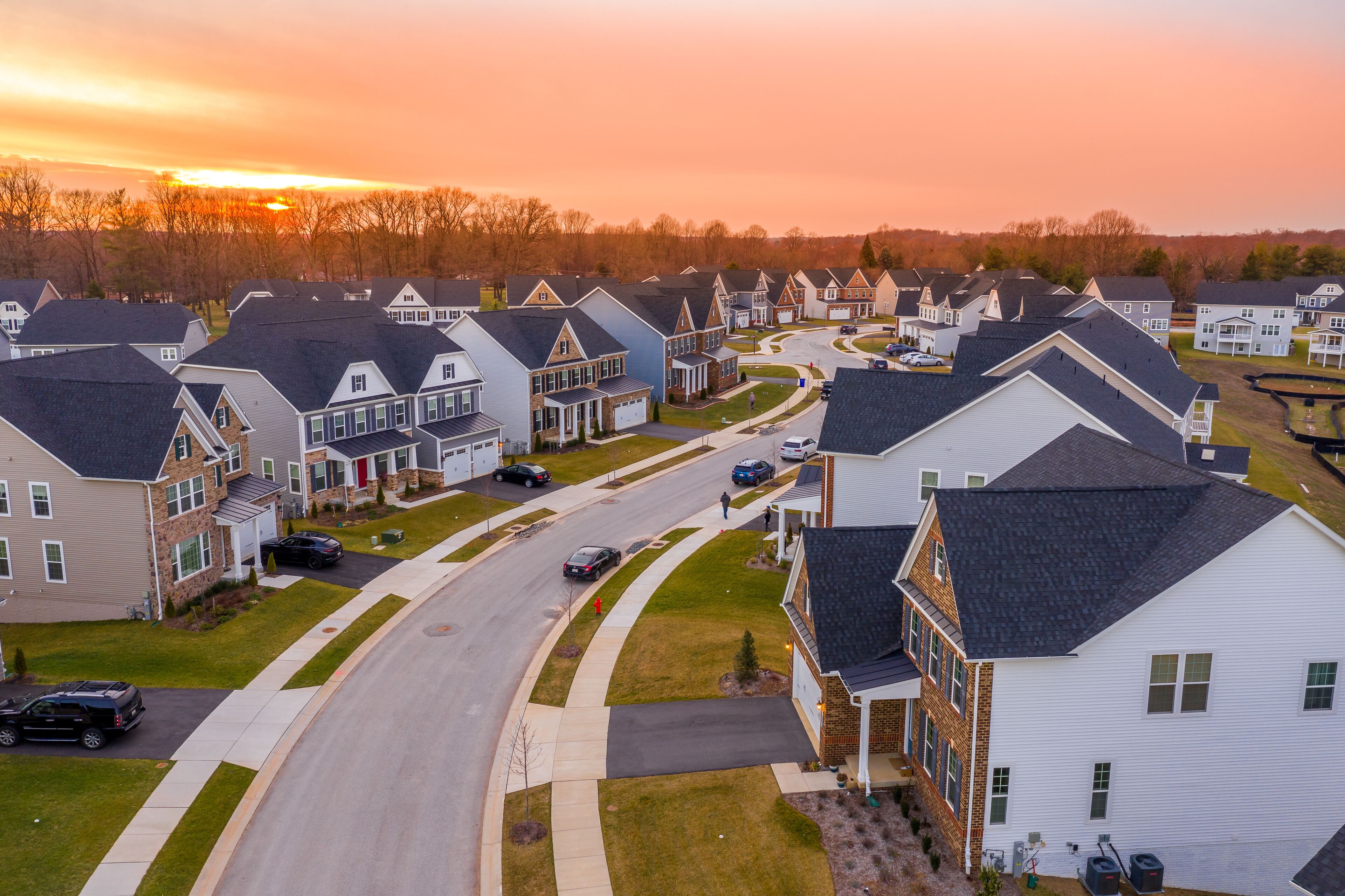Aerial sunset panorama of luxury real estate development single family house neighborhood curving street with dramatic sky in Maryland USA