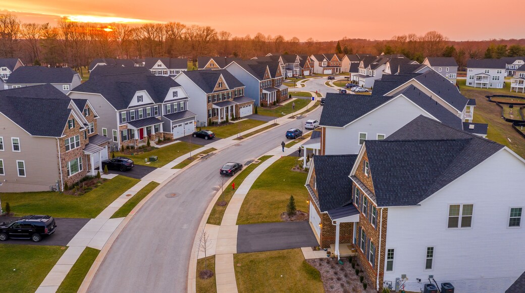 Aerial sunset panorama of luxury real estate development single family house neighborhood curving street with dramatic sky in Maryland USA