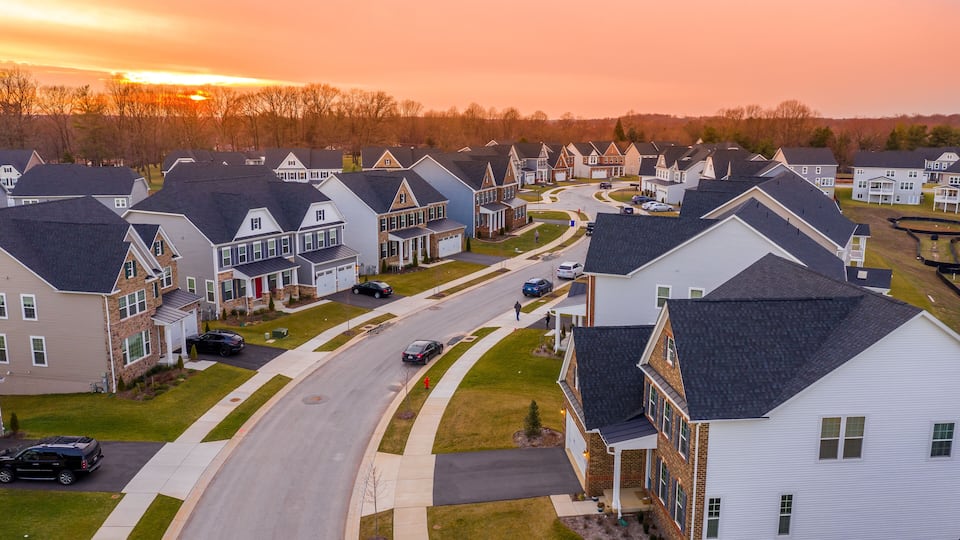 A suburban neighborhood with houses, a winding road, and a sunset.