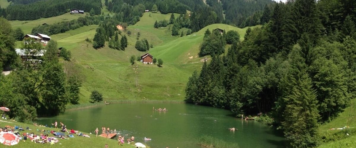 A lake surrounded by green hills and a mountain in the background.