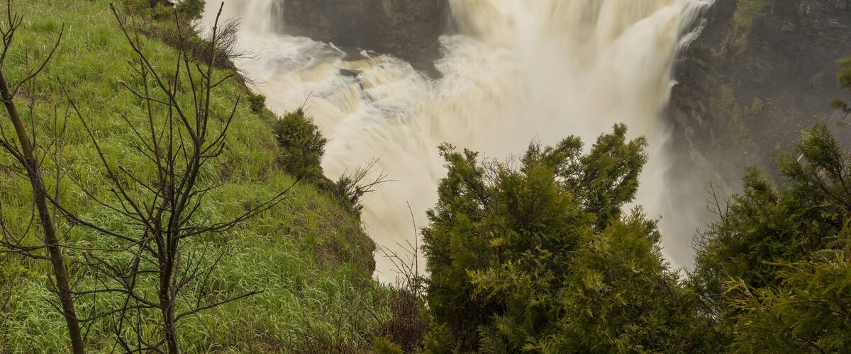 A large waterfall with a bridge in the background.