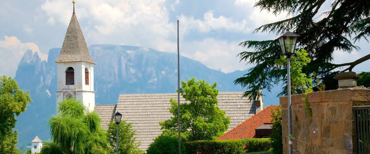 A church with a bell tower, a stone wall, and a cobblestone path.