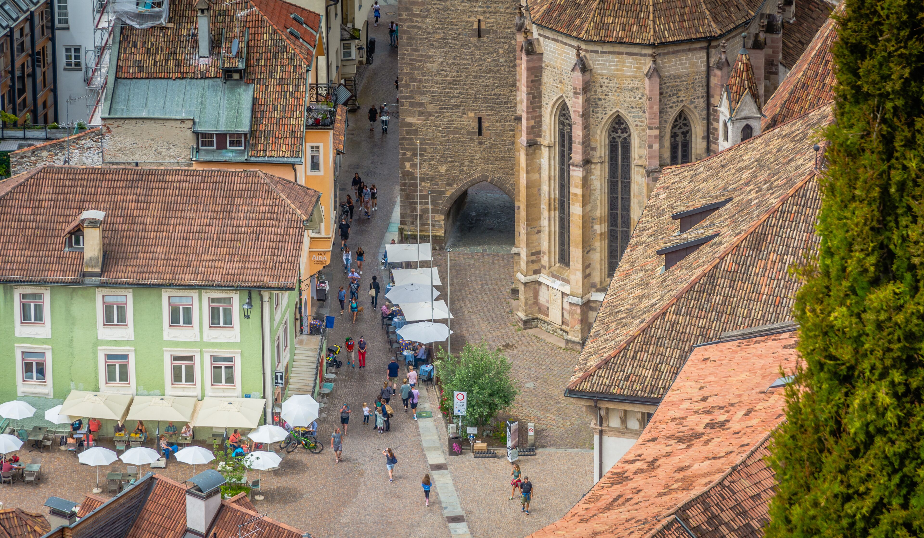 Una calle adoquinada con edificios históricos, una iglesia y zonas de estar al aire libre.