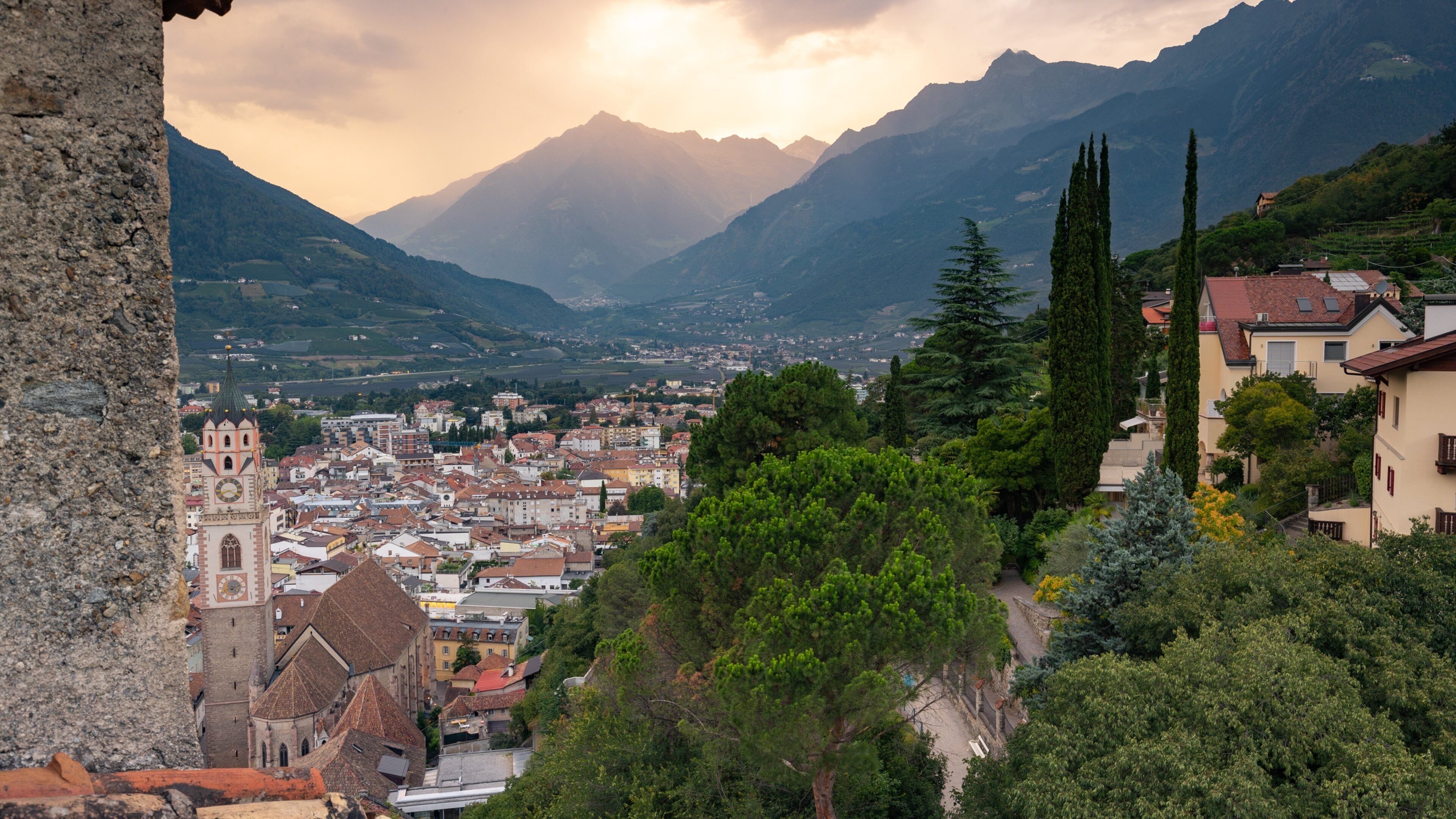 A town nestled in a valley with mountains in the background, a prominent church, and a mix of residential and commercial buildings.