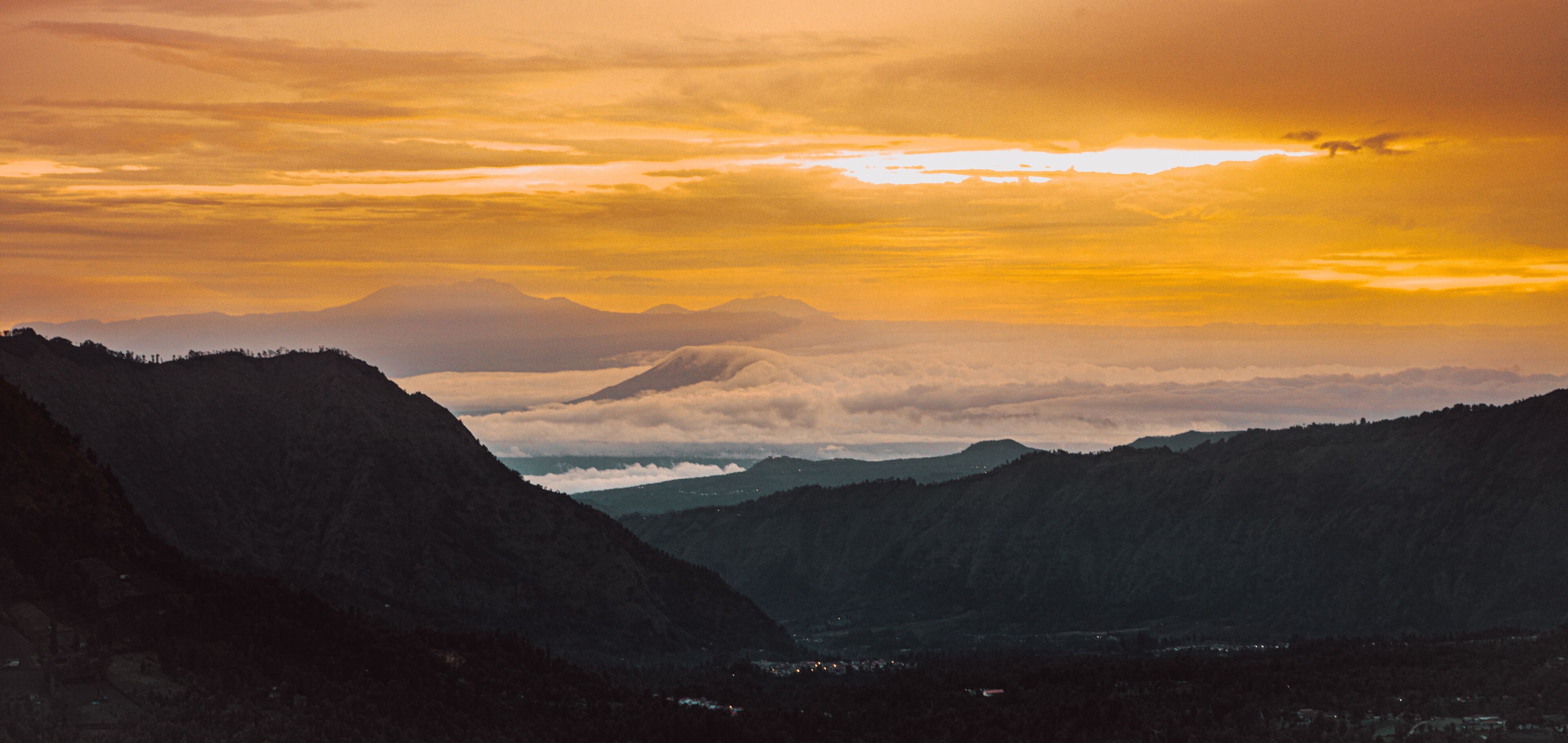 A mountain range with a sunset and clouds.