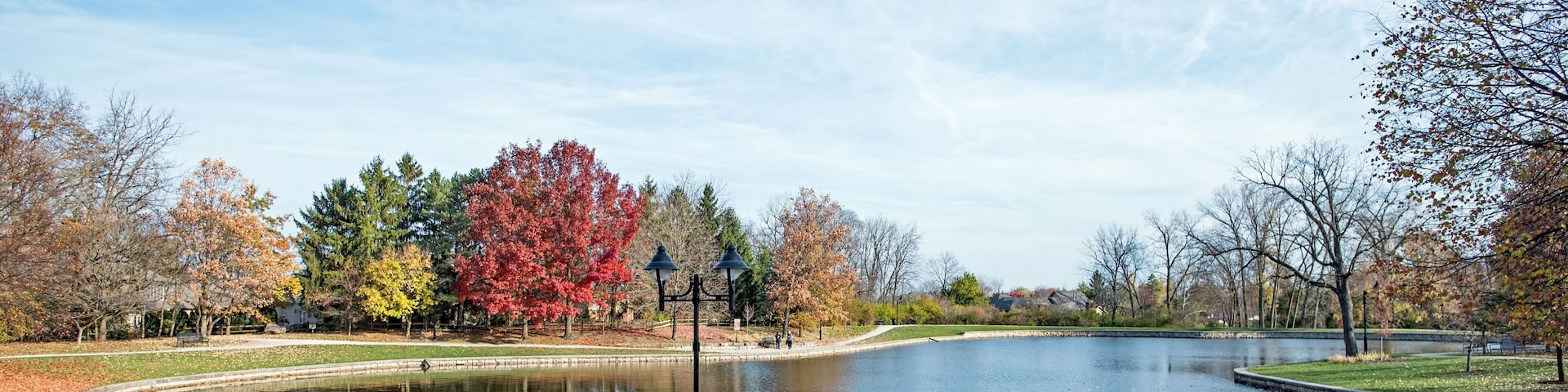 A park with a pond, autumn trees, and a walking path.