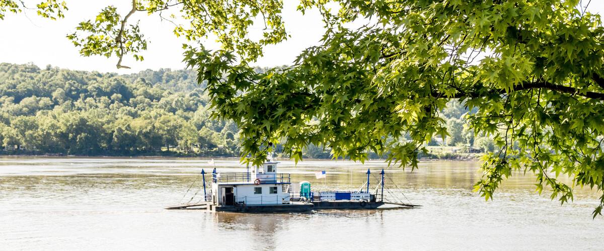 A floating dock with a small building and an American flag, surrounded by calm water and dense green foliage.