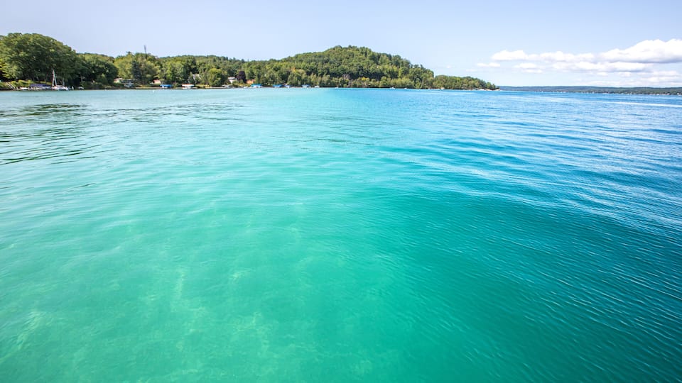 A clear turquoise lake with a forested island in the background.