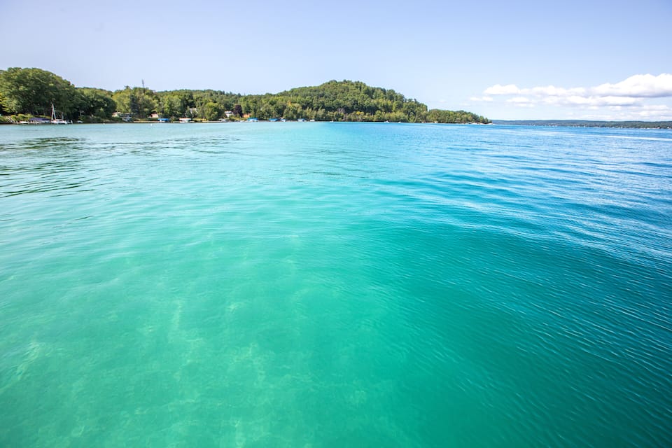 A clear turquoise lake with a forested island in the background.
