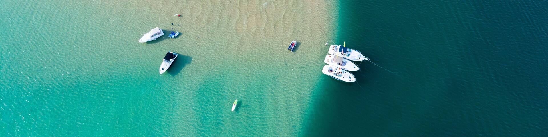 An aerial view of a turquoise sea with boats anchored near the shore.