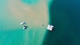 An aerial view of a turquoise sea with boats anchored near the shore.