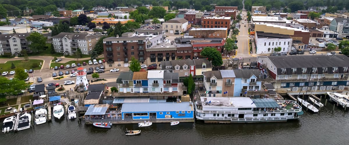 A riverside town with a dock, boats, and buildings.