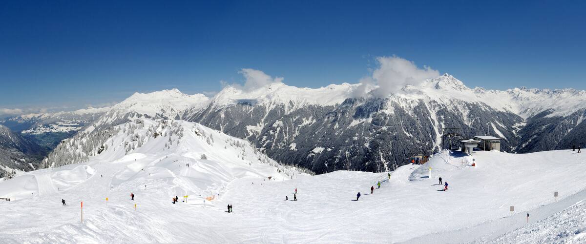 A snow-covered mountain with skiers and a ski lift.