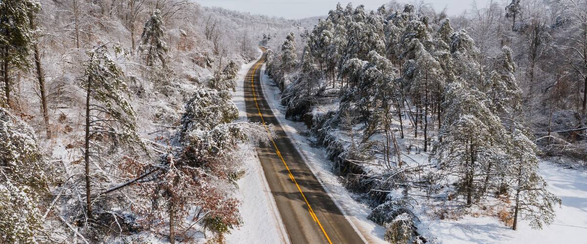 A snow-covered road winding through a forest.