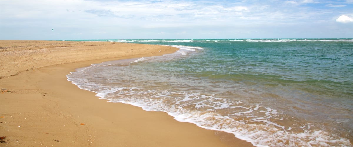 A sandy beach with gentle waves and a clear blue sky.