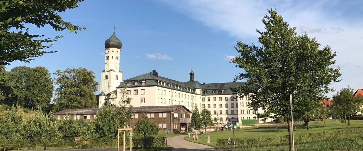 A large building with a clock tower, surrounded by trees and a grassy area.