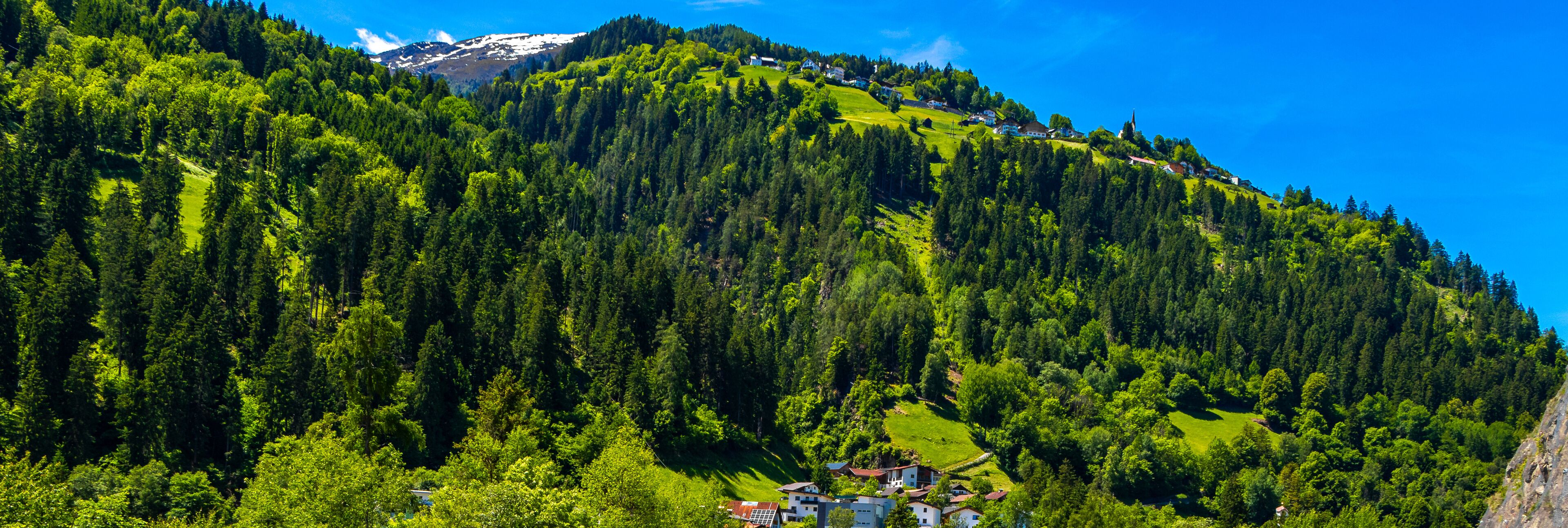 A mountainous landscape with dense forests and a small village nestled in the valley.