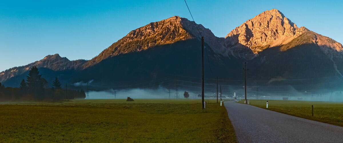 A road leading to a mountain range with a clear sky.