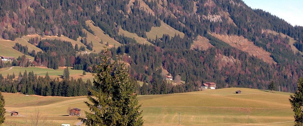 A mountain with a rocky peak, surrounded by forested hills and scattered houses.