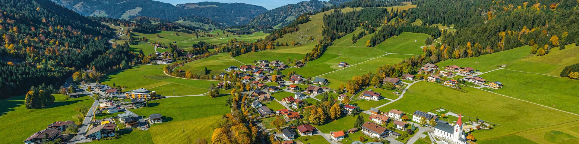 A rural village nestled in a valley with houses, roads, and surrounding hills.