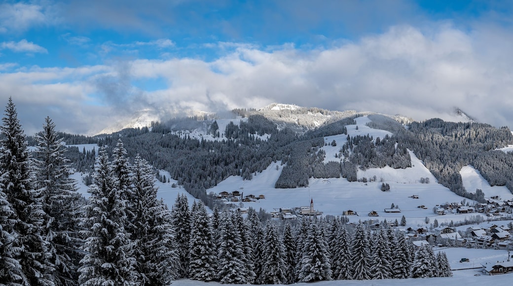 A snow-covered mountain landscape with a ski resort and a clear blue sky.