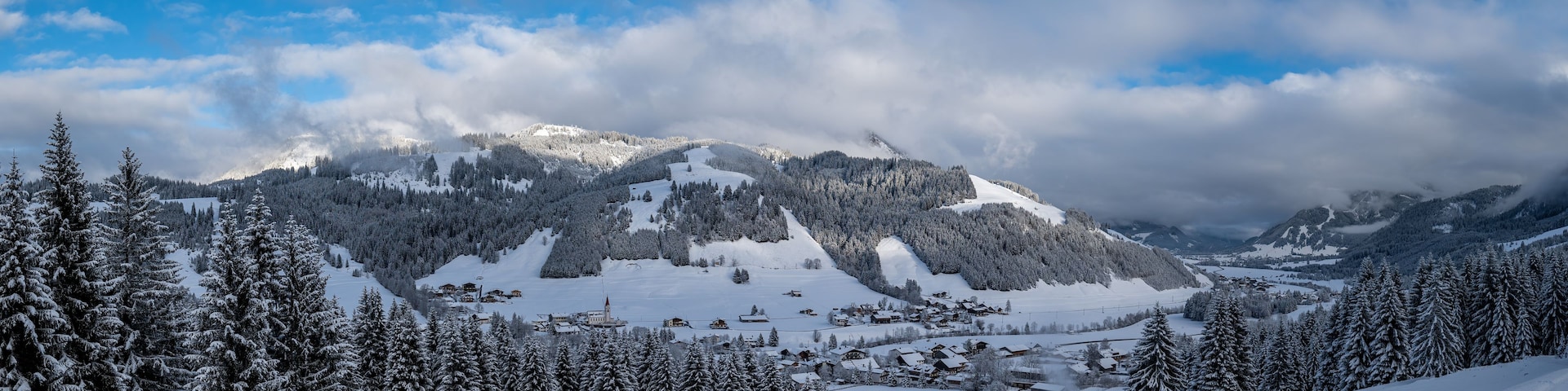 A snow-covered mountain landscape with a ski resort and a clear blue sky.