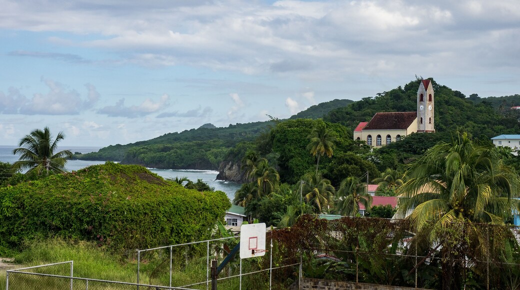 A coastal landscape with a church on a hill, palm trees, and a basketball court.