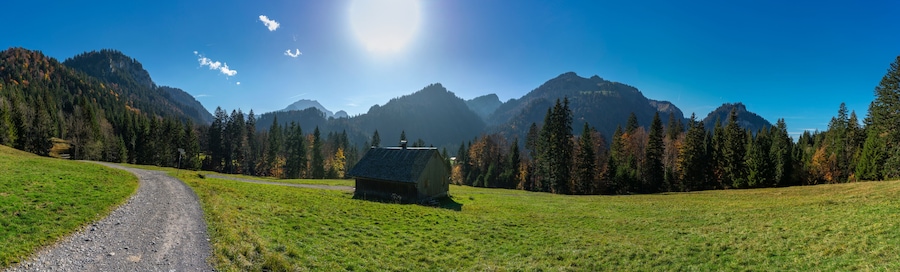 schöne hölzerne Alphütte am Weg von Sibratsgfäll nach Schönenbach. Herbst im Bregenzerwald, Österreich. Holzhaus, Stadel, Alp, am Wegrand. Berge mit herbstlich bunten Wäldern im Hintergrund
