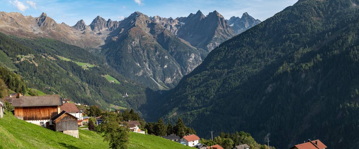 A mountainous landscape with a valley, houses, and a prominent peak.
