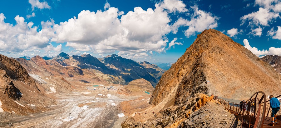 A mountain landscape with a prominent peak, a valley with a glacier, and a cable car system.