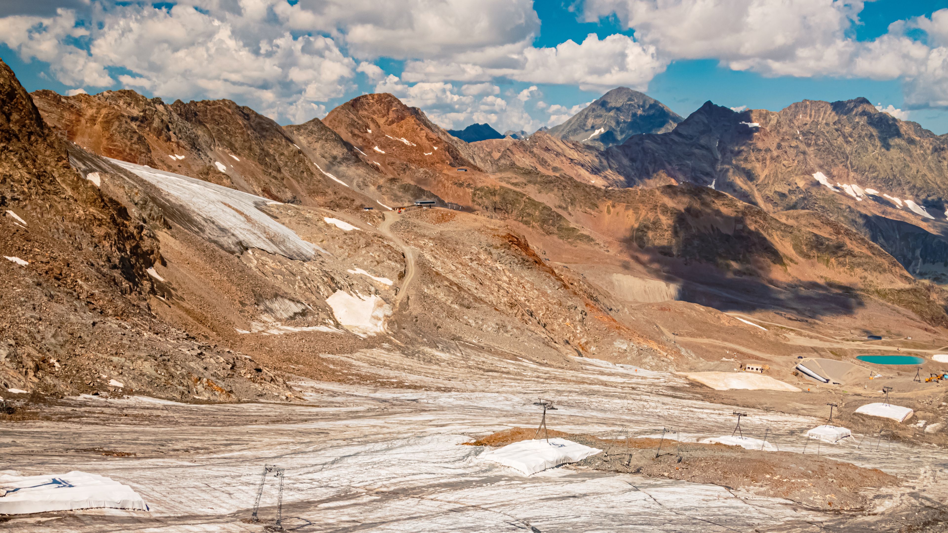 A mountainous landscape with snow patches, a clear sky, and distant peaks.