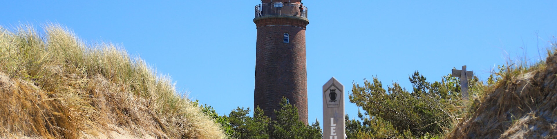 Camino que lleva a un faro, con una cruz al fondo.