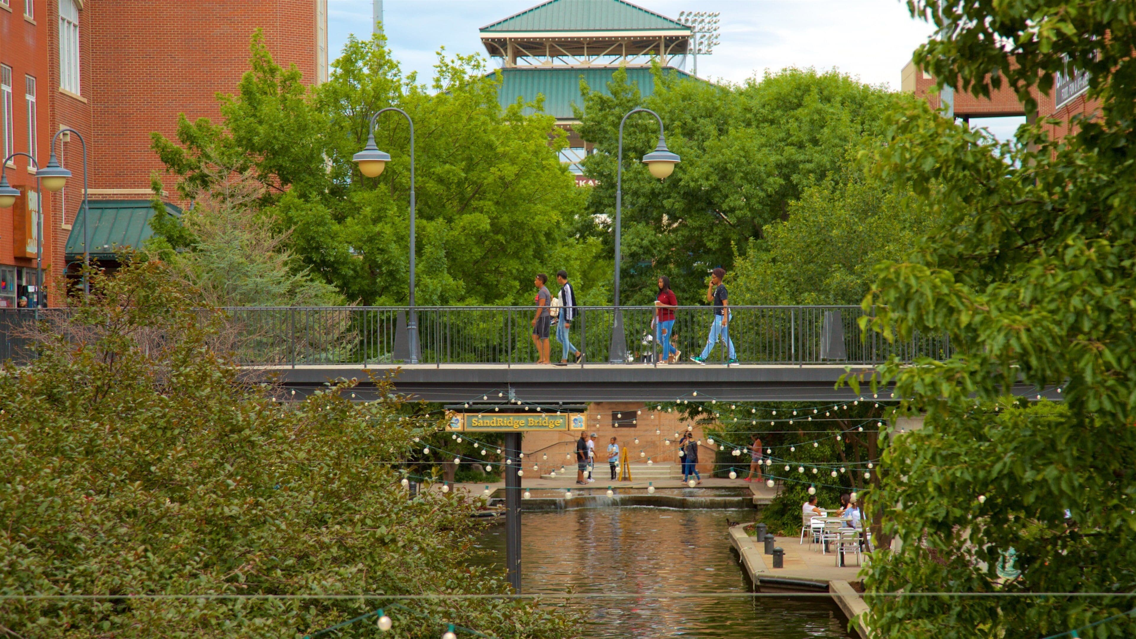 Bricktown which includes a bridge and a river or creek as well as a small group of people