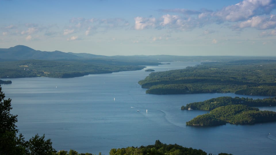 A large body of water surrounded by forested hills and mountains.