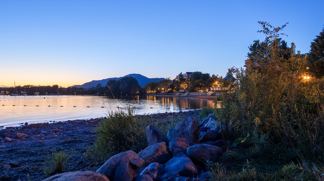 Beautiful Magog town at night in reflections of Memphremagog lake. Canadian romantic landscape with mountains, lake, night sky and awesome water background.