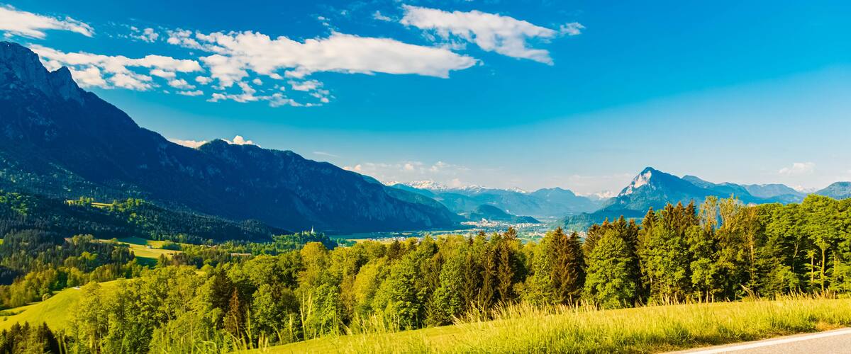 A mountainous landscape with a clear sky, a road, and a town in the valley.