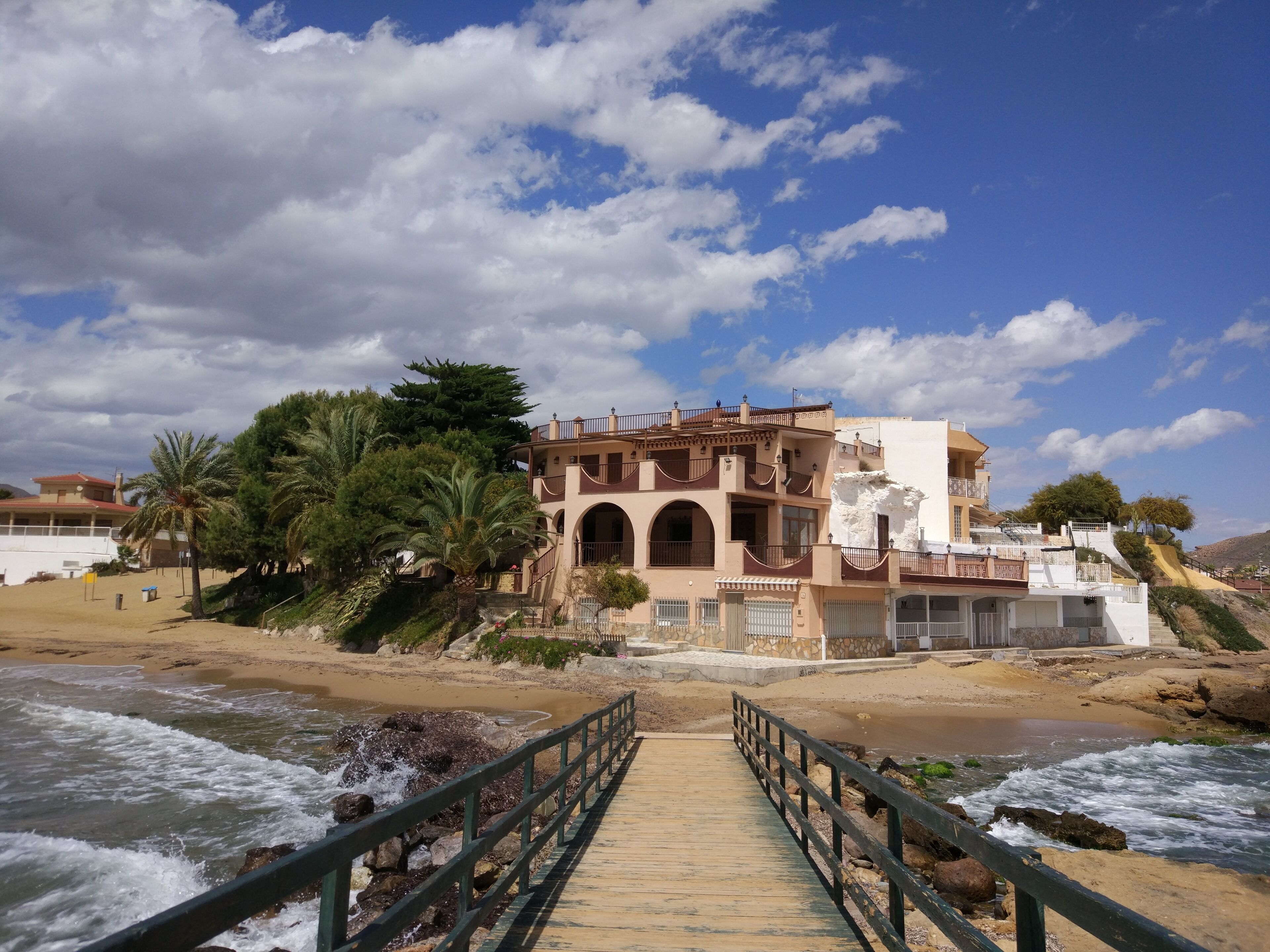 A coastal building with a wooden walkway leading to it.