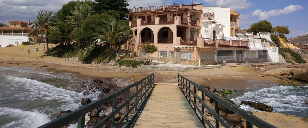 A coastal building with a wooden walkway leading to it.