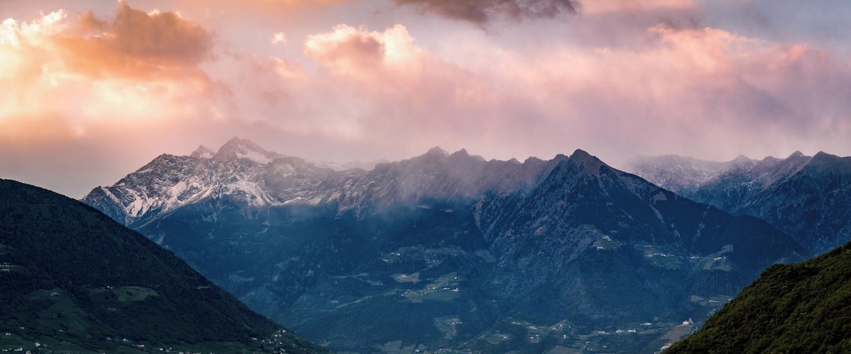 A mountain range with snow-capped peaks and a valley below.