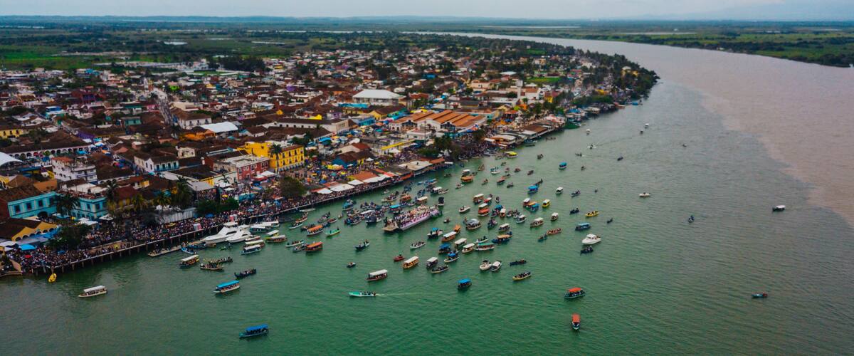 A coastal town with a river filled with boats, colorful buildings, and a distant view of the landscape.