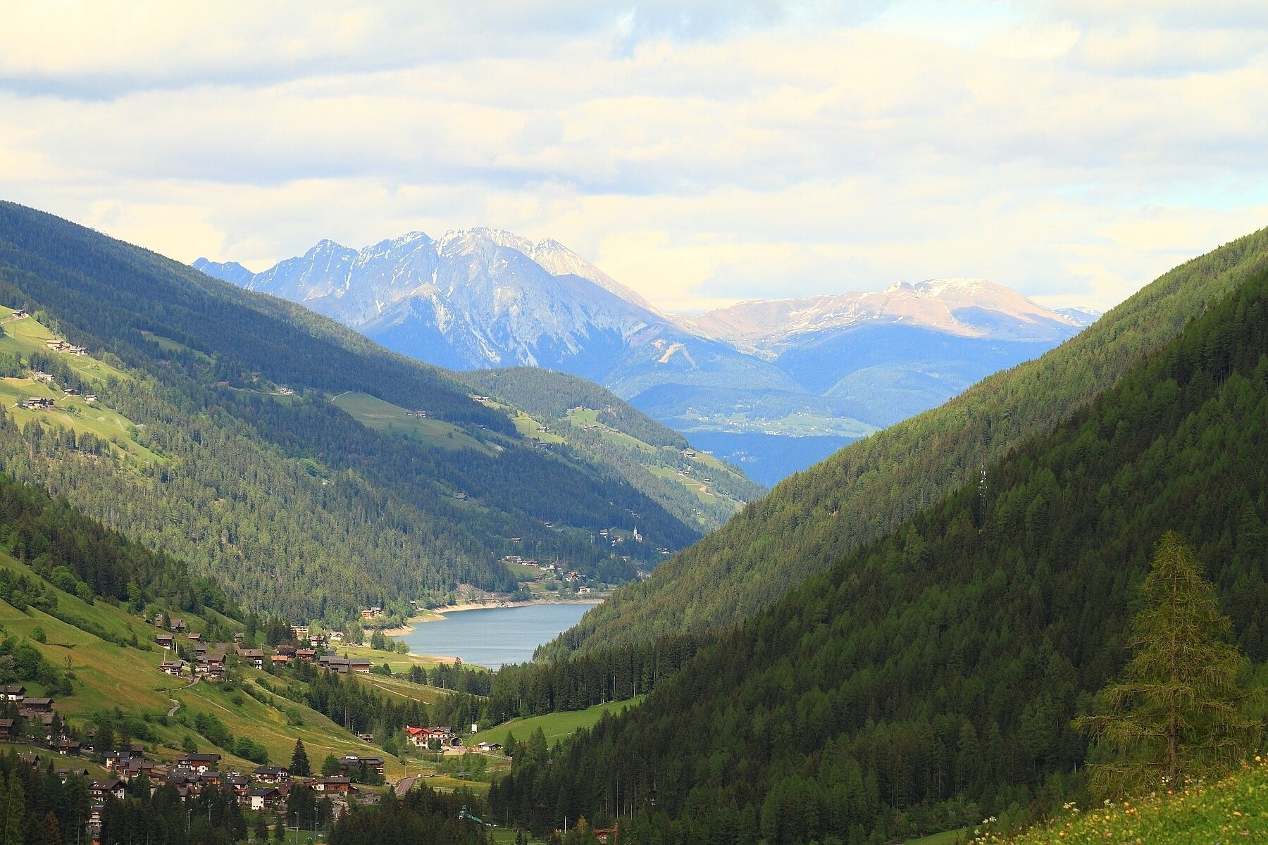 A mountainous landscape with a lake, houses, and a church.