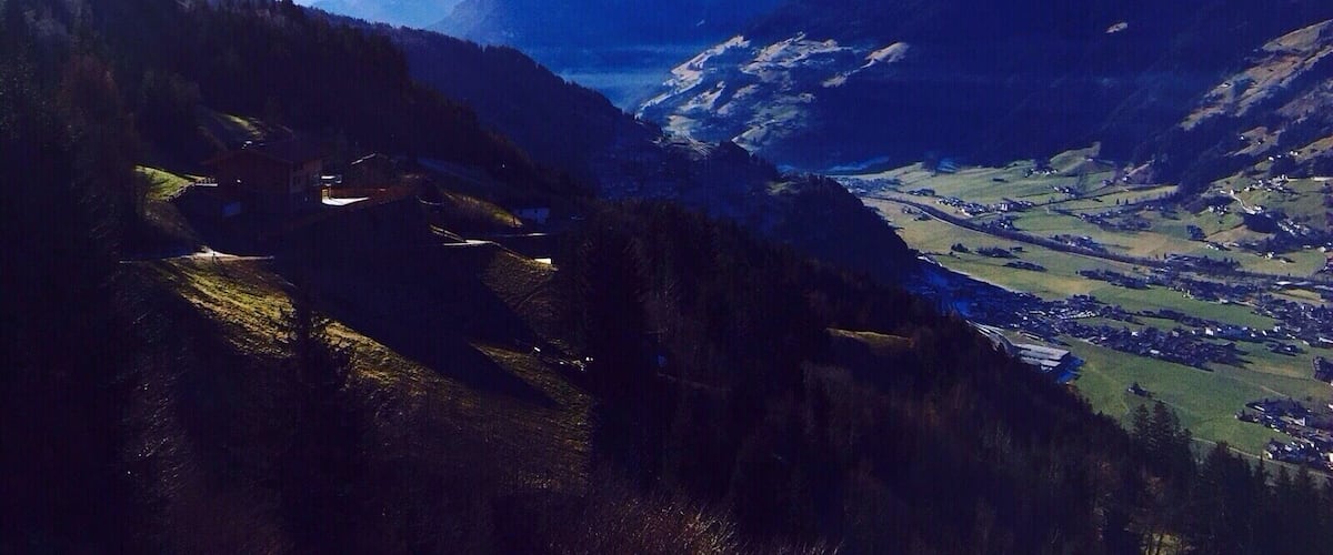 A mountainous landscape with a valley, a lake, and snow-capped peaks.
